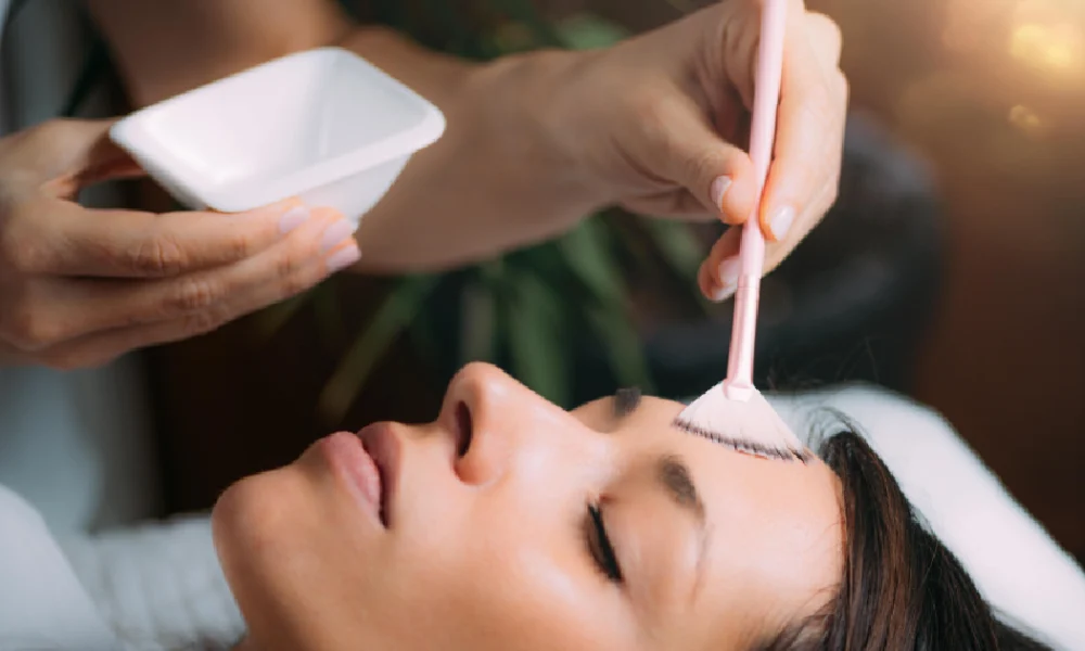 Woman receiving a facial peel treatment with a brush applicator on her forehead in a professional skincare in Texas